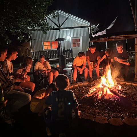 Gruppe sitzt abends gemeinsam am Lagerfeuer im Ökodorf